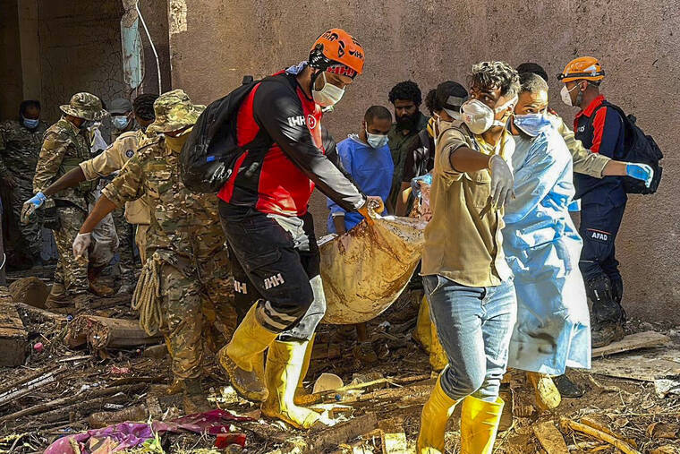 In this photo provided by Turkey’s IHH humanitarian aid group, rescuers retrieve the body of a flooding victim in Derna, Libya, Wednesday, Sept.13, 2023. Search teams are combing streets,